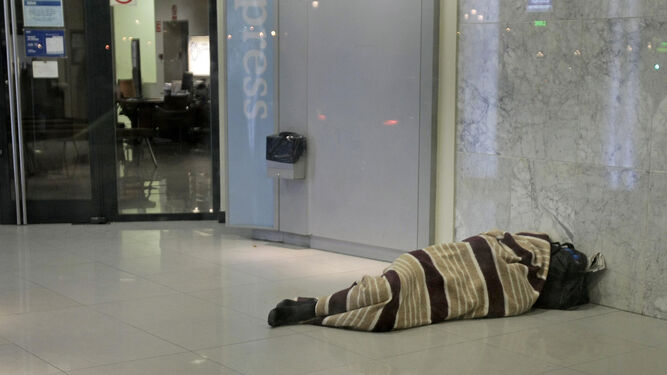 Una persona arropada en una manta duerme en el cajero de un banco, en una imagen de archivo.