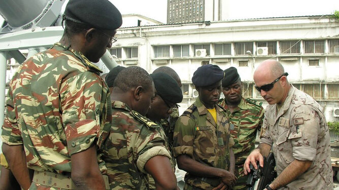 Un infante de Marina español instruye a soldados cameruneses en las características de un fusil de asalto.