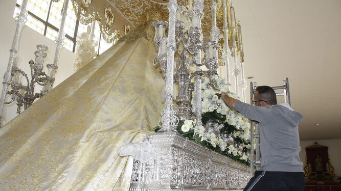 Un hermano da los últimos retoques al exorno floral que llevará hoy el palio de Nuestra Señora de la Entrega.