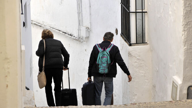Dos turistas, con sus maletas, por una de las calles del casco antiguo de Arcos.