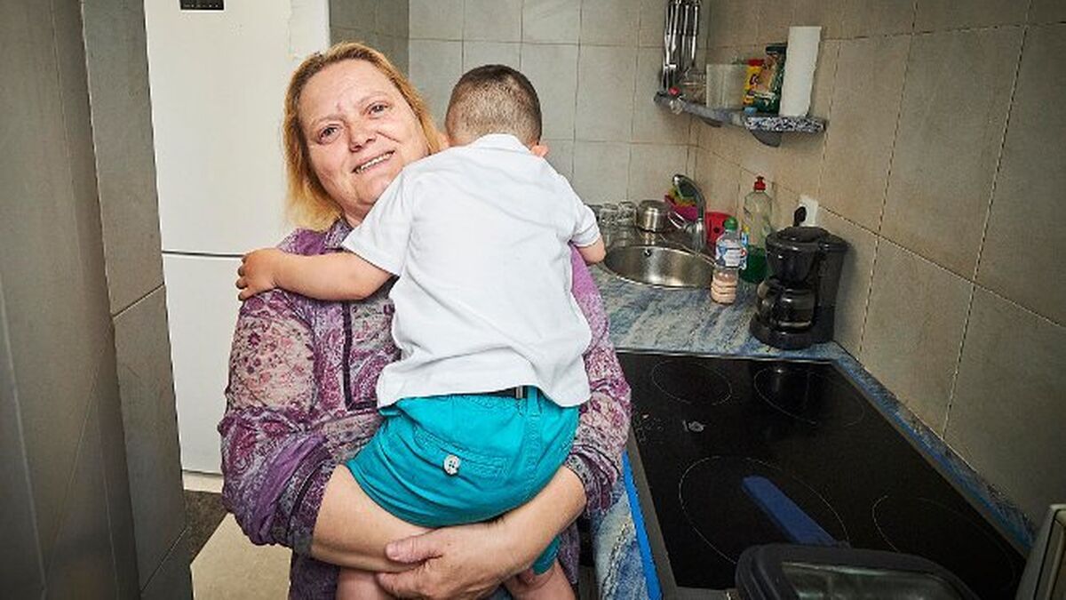 Ana coge en brazos a su nieto en la casa en la que ambos residen, ubicada en el barrio de La Viña.