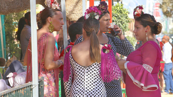 Varias mujeres con sus trajes de flamenca en la entrada de una caseta.