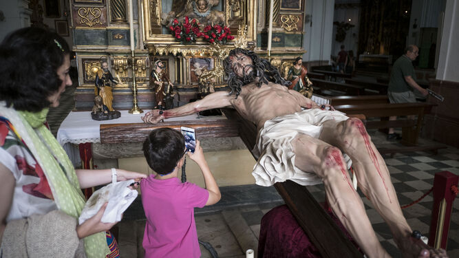 Un niño fotografía con su móvil la imagen del Cristo del Perdón en la Iglesia de San Francisco.