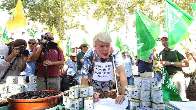 Un falso Donald Trump firma un manifiesto en defensa de la aceituna negra en una protesta en Sevilla.