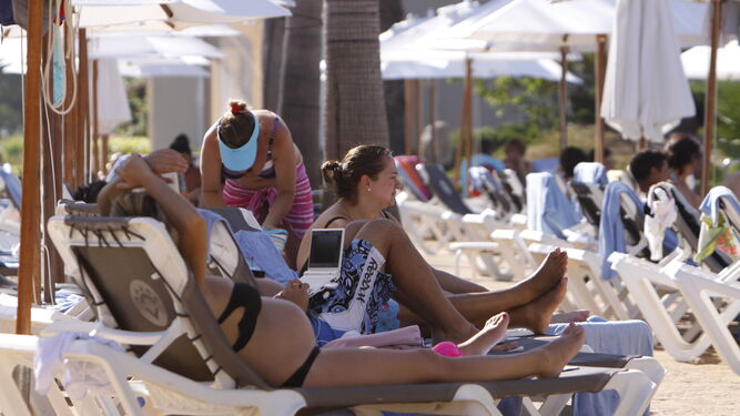 Turistas toman el sol en la piscina de un hotel en Chiclana.