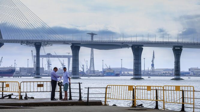 El candidato del PP a la Alcaldía, Juan José Ortiz, conversa con una persona junto a las barandillas rotas en el paseo marítimo de Astilleros.