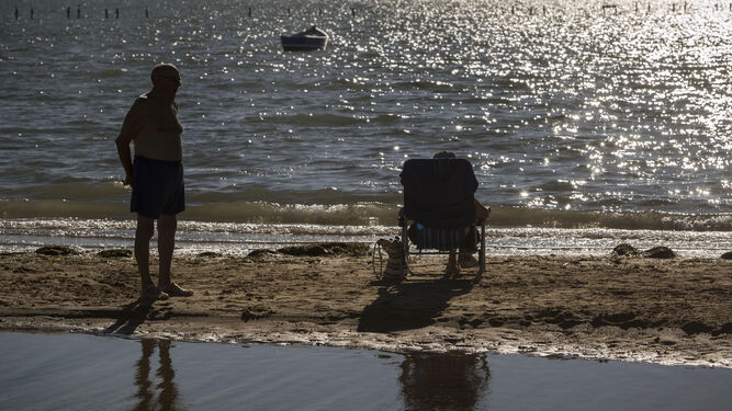 Una pareja contempla el atardecer en la playa de La Casería.