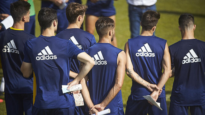 Varios jugadores del primer equipo atienden a la charla técnica durante un entrenamiento en El Rosal.