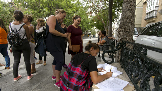 Una madre de alumno firma las reivindicaciones del colectivo en un banco de la plaza de Mina.