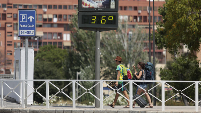 Dos turistas pasan por debajo de un termómetro en la capital con 36 grados.