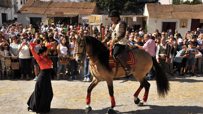Una mujer y un caballo bailando al compás ante la mirada de numerosas personas.