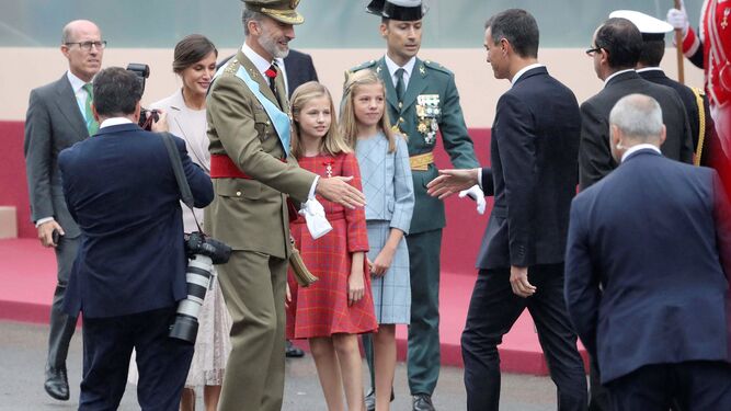 El rey Felipe, junto sus hijas, se dispone a saludar al presidente del Gobierno, a su llegada ayer a la madrileña Plaza de Lima para presidir el desfile del 12-O.