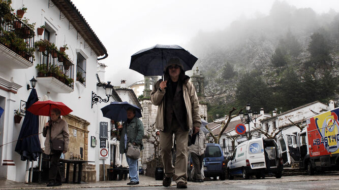 Varios turistas pasean por Grazalema un día de lluvia.