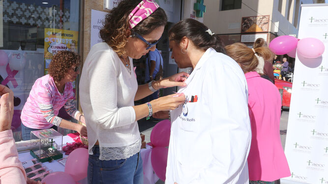 Voluntarias colocan lazos rosa en la Plaza de Las Bodegas.