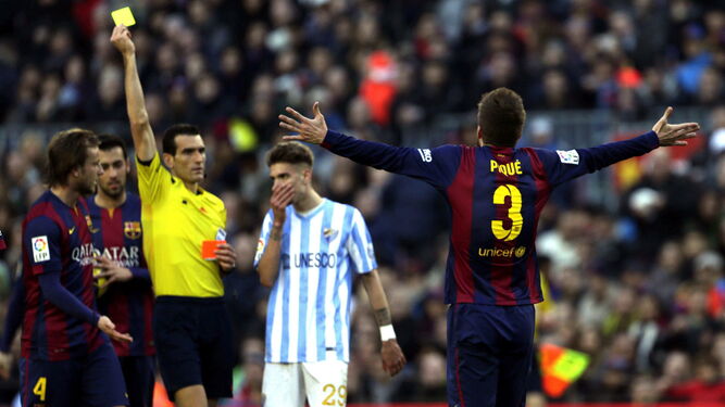 Martínez Munuera enseña una tarjeta amarilla a Piqué en el Camp Nou.