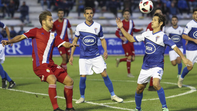 Pablo Sánchez intenta bajar un balón en el área onubense ante la mirada de Ramos.