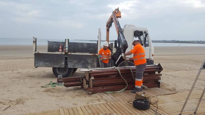 Imagen de dos trabajadores del Servicio Municipal de Playa desmontando las instalaciones.