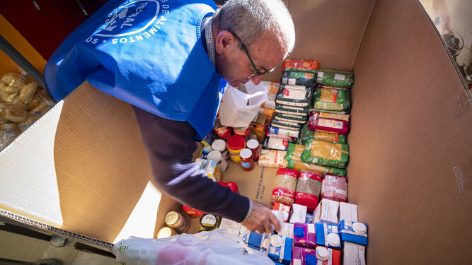 Uno de los voluntarios del Banco de Alimentos organizando los productos donados en un supermercado de Cádiz.
