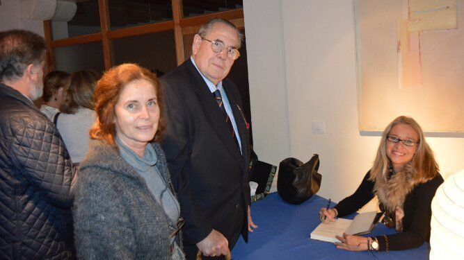 La escritora Almudena de Arteaga firmando un ejemplar a Luis de Mora-Figueroa y Carmen Príes.