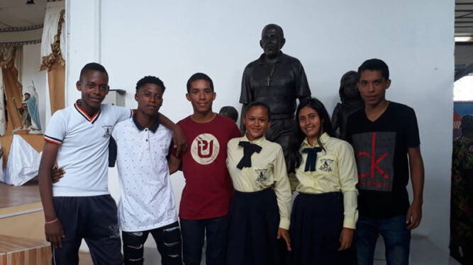 Seis de los siete jóvenes que salvó el religioso, junto a una réplica de la estatua.