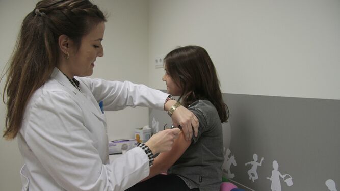 Imagen de archivo de una especialista vacunando a una niña.