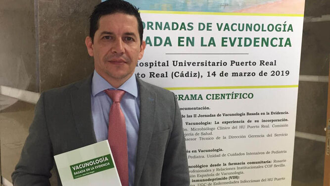 D.C. Jesús Ruiz Aragón ante el cartel de las Jornadas de Vacunología Basada en la Evidencia, en el Hospital de Puerto Real.