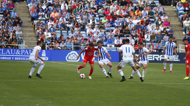 Pablo Sánchez protege el esférico rodeado por jugadores del Recreativo de Huelva.