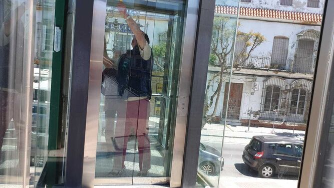 El hombre, encerrado junto a una mujer, manipula la puerta para salir de ascensor.