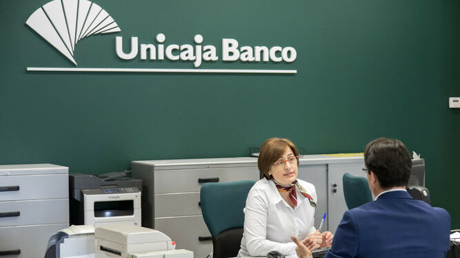 Una empleada de Unicaja atiende a un cliente.