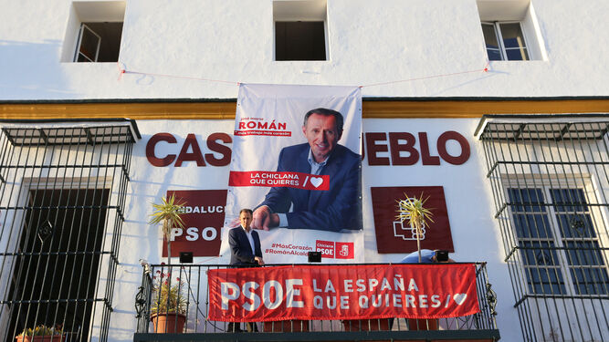 Román junto al enorme cartel con su rostro en la fachada de la sede socialista.