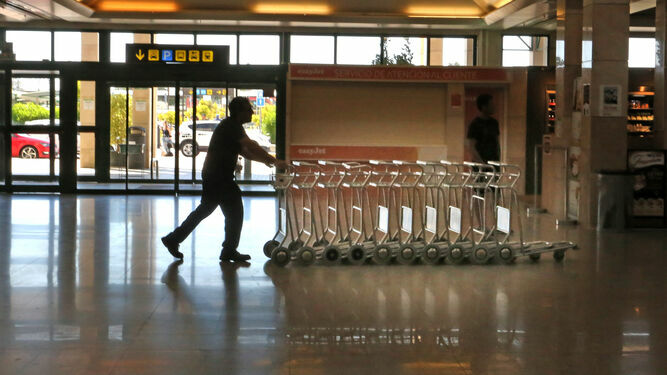 Un trabajador del aeropuerto empuja unos carritos por la terminal.