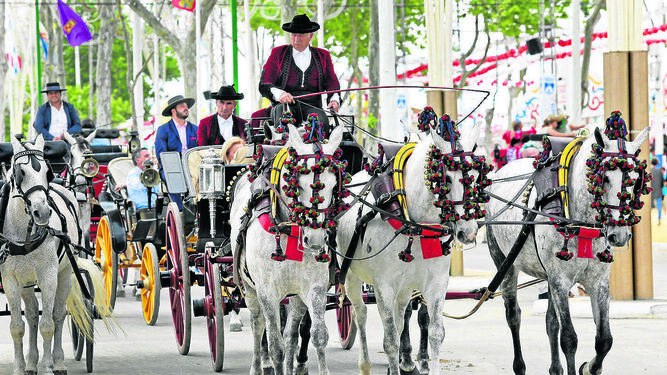 Los carruajes pasan por una calle libre de suciedad en la Feria de El Puerto.