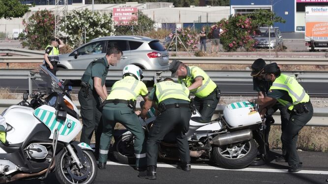 Varios guardias civiles incorporan una motocicleta en el lugar del accidente.