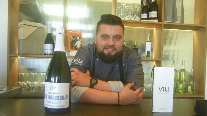 Juan Viu posando en su restaurante ante una botella de Toto Barbadillo, un espumoso especial de la firma sanluqueña.