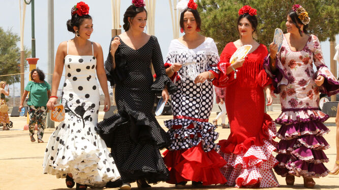 Un grupo de mujeres con trajes de flamenca pasean por el ferial de Las Albinas.