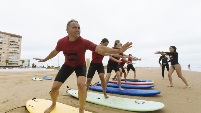 Instructores de la escuela Cádiz Surf Center con un grupo de alumnos extranjeros este lunes en la playa Victoria.