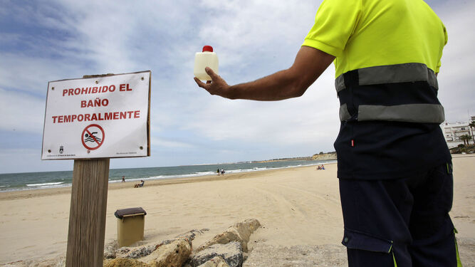 Un operario, esta mañana con muestras de agua de la playa de Fuentebravía para su análisis.