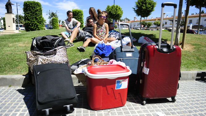 Un grupo de viajeros espera el autobús al inicio de sus vacaciones de verano / M.G.