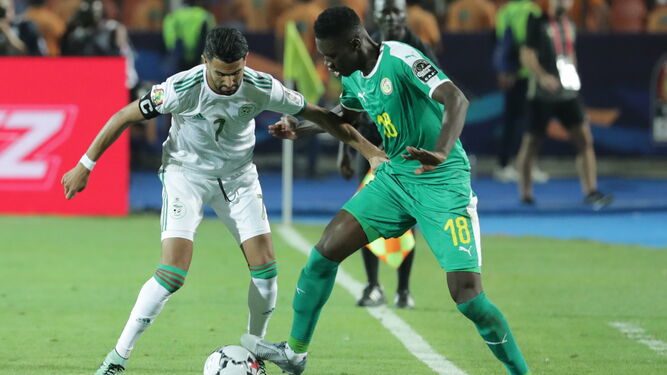 Mahrez, la estrella de la selección argelina, disputa el balón con el senegalés Sarr.