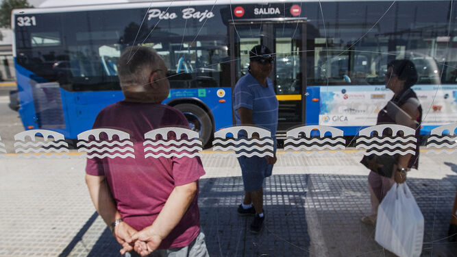 Ciudadanos en una marquesina mientras pasa una de las líneas del autobús urbano.