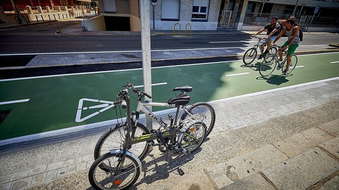 Dos bicicletas aparecen amarradas a una señal junto al carril para estos vehículos.