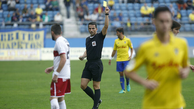 Ais Reig muestra una cartulina amarilla a un jugador del Cádiz en el partido frente al Huesca de la temporada 2016/17.