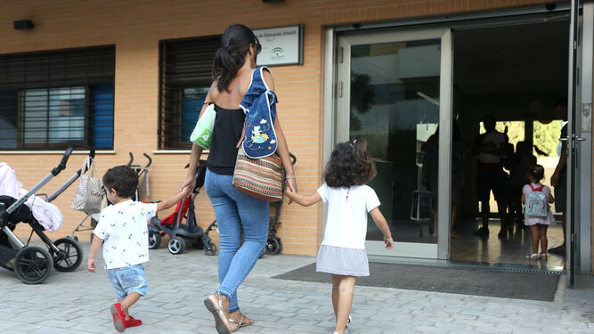 Una madre lleva a sus hijos a una escuela infantil.