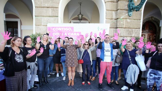 Personas con las palmas de las manos en rosa apoyando la campaña de la AECC en la plaza de San Juan de Dios.