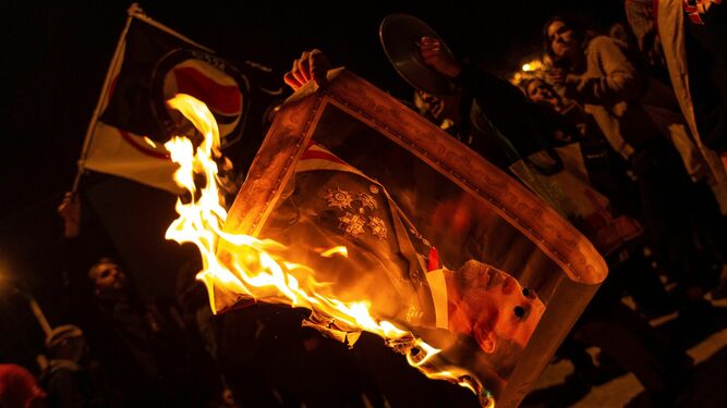 Varios manifestantes quemando fotos del rey Felipe VI durante la protesta esta noche en la avenida Diagonal de Barcelona.