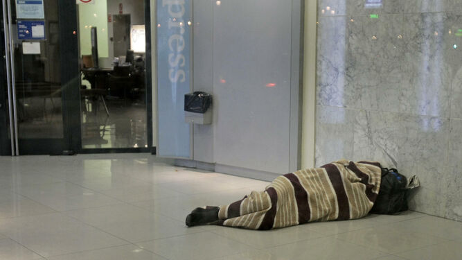 Una persona sin hogar duerme en un cajero de la capital gaditana.