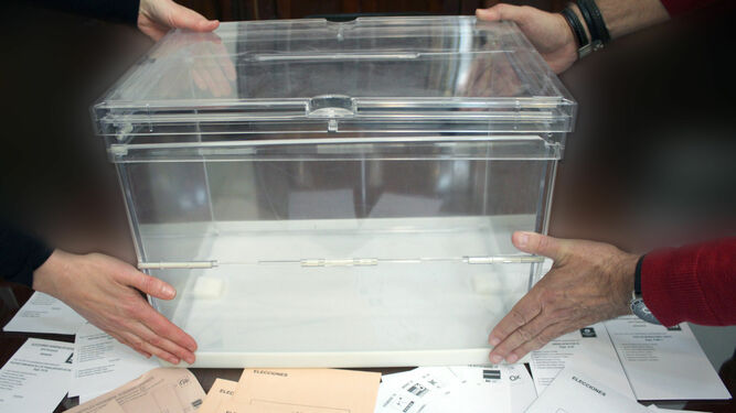 Dos miembros de una mesa electoral colocan la urna que servirá para depositar los votos.