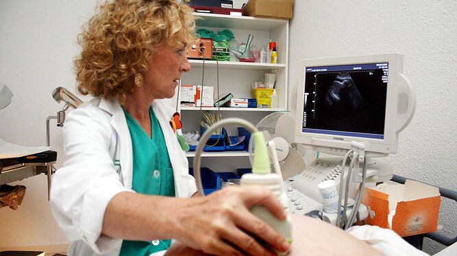 Una profesional sanitaria realiza una ecografía a una mujer embarazada.