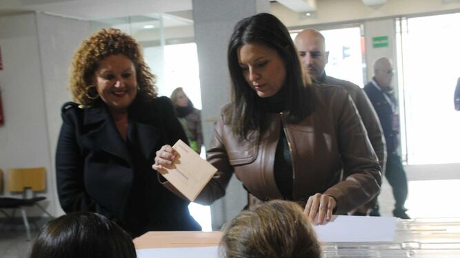 Patricia Cavada introduce su voto en las urnas, ante la mirada de Araceli Maese.