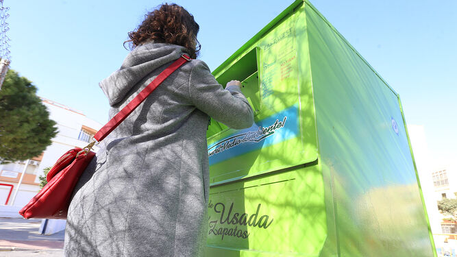 Una mujer deposita prendas en uno de los contenedores de ropa usada.